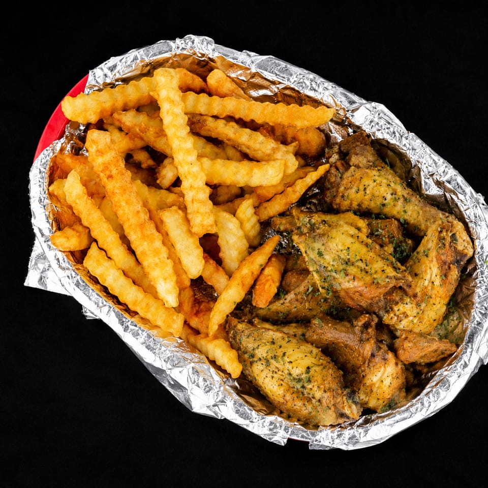 Crispy crinkle-cut fries and seasoned chicken wings in a foil-lined takeout container.